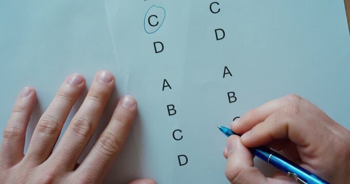 Close-up of a person marking the correct answer on a multiple-choice questionnaire. Education, examination, assessment, learning, and testing concept.