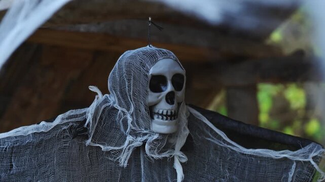 Skull figure draped in torn mesh cloth as eerie Halloween decor on wooden background, seasonal spooky theme. 4K.
