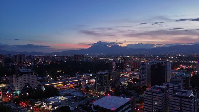 Vista de altura de Ciudad de Guatemala con rascacielos residenciales y luces urbanas de noche. Atardecer dram&aacute;tico y colorido sobre el horizonte de la Ciudad de Guatemala.