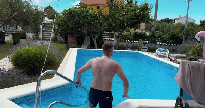 A man covered in sunscreen stands at a pool and explains that swimming is not allowed with excessive sunscreen residue. Focus on pool rules, hygiene, and guest guidance in a resort setting.