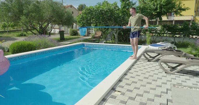 A man using a net to clean a swimming pool by removing debris and unwanted objects from the water. Focus on pool maintenance, cleanliness, and outdoor care.