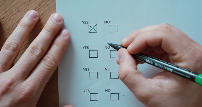 Close-up of a person marking the "Yes" option on a questionnaire or survey form. Decision making, voting, approval, feedback, and form completion concept.