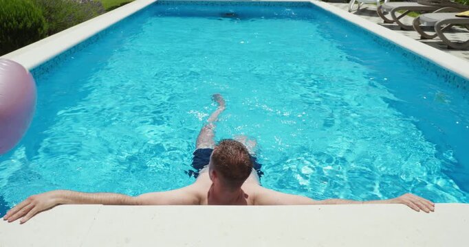 Man resting at the edge of a swimming pool while enjoying a relaxing moment in the water. Summer leisure, wellness, recreation, and vacation lifestyle concept.