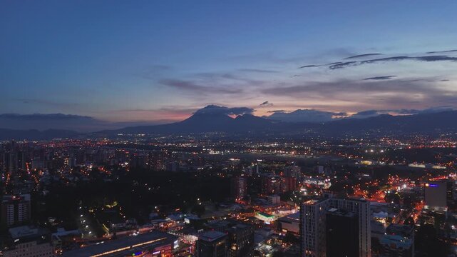 Vista de altura de Ciudad de Guatemala con rascacielos residenciales y luces urbanas de noche. Atardecer dram&aacute;tico y colorido sobre el horizonte de la Ciudad de Guatemala.
