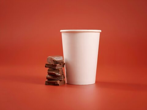 White paper cup with stack of chocolate bars on red background