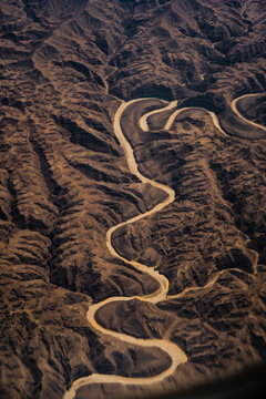Aerial view of a winding river cutting through the rugged, arid landscape of the terrain in Nairobi, Nairobi County, Kenya.