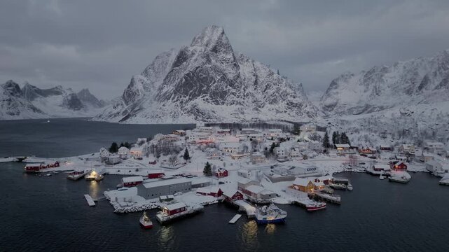 Aerial twilight view of snowy fishing village and harbor on rocky coastal inlet