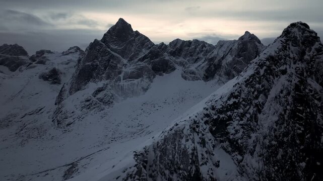 Aerial view of rugged snow-covered mountain peaks at dusk