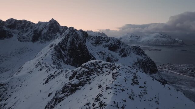 Aerial sunset over snow-covered coastal mountain ridge
