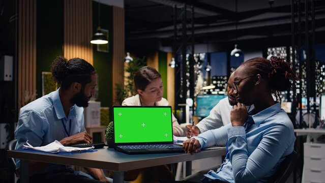 Green screen mockup laptop used by staff members in modern inclusive office, Coworkers presenting team leader key data statistics on chroma key isolated screen device after business audit.