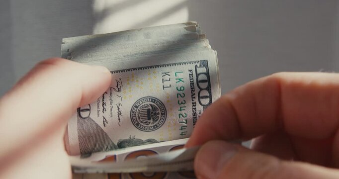 Hands counting a stack of one hundred dollar bills