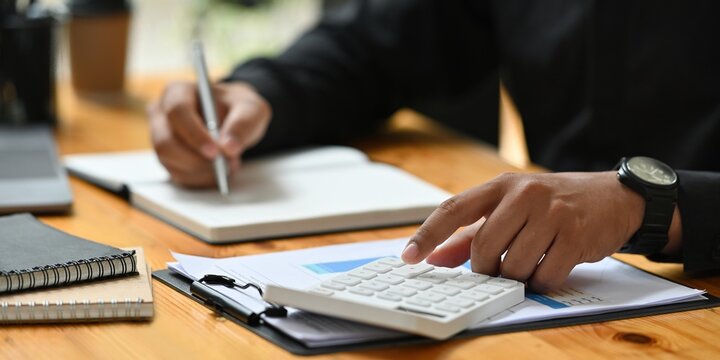 Closeup of a businessman calculating financial data and taking notes