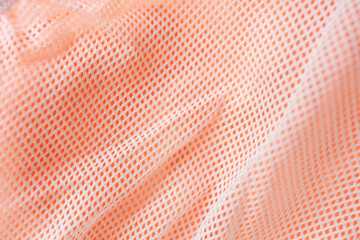 White mesh fabric over bright orange textile creating breathable sports material texture