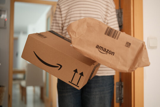 Alicante, Spain - February 02, 2026: Woman Holding Amazon Delivery Packages at Home Entrance Door After Online Order