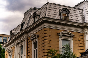 Historic eclectic villa with Mansard roof and dormer windows against cloudy sky, architectural heritage photography. © Khalil