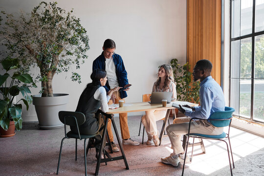 Diverse business team collaborating during an informal meeting in a modern eco-friendly office. Discussing project strategy. Developing innovative ideas