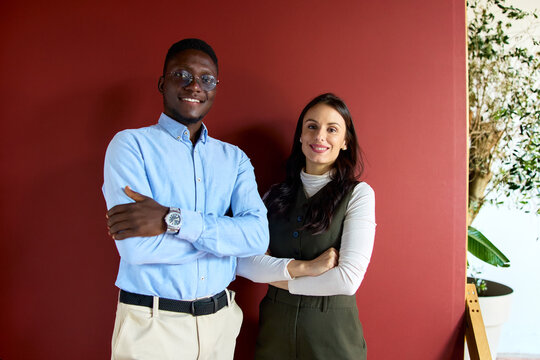 Diverse business professionals smiling and looking at the camera with arms crossed. Symbolizing confidence. Success. And collaboration within a modern professional setting