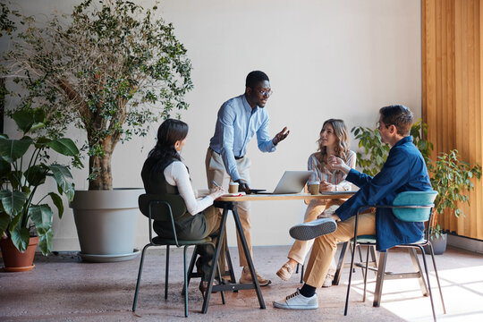 Diverse business team collaborating and brainstorming in a modern office space, discussing new ideas and strategy during a casual meeting