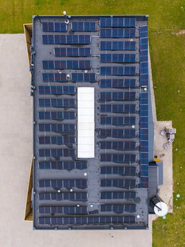 Aerial view of artisanal cheese factory roof covered with rows of solar panels surrounded by green fields in Ikskile, Ogre Municipality, Latvia.