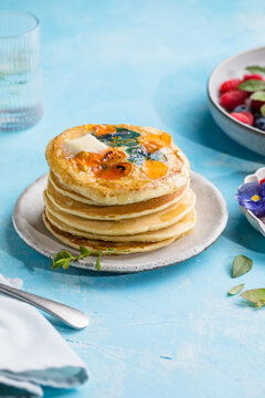 Top view of homemade pancakes with embedded edible pansy flowers and honey butter