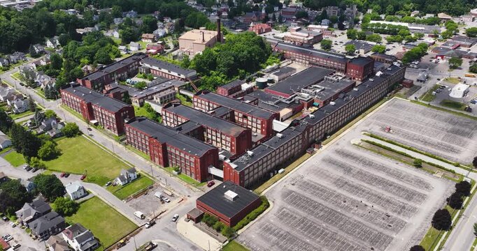 LLION, NY, USA - June 24, 2026: Afternoon summer aerial video of downtown, business district, LLION, NY.  Former Remington Arms factory brick building.