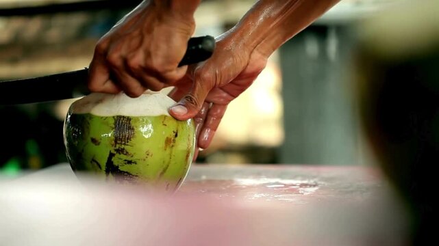 A man opening coconut with a big knife.