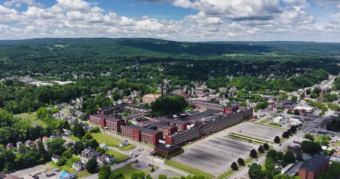 LLION, NY, USA - June 24, 2026: Afternoon summer aerial video of downtown, business district, LLION, NY.  Former Remington Arms factory brick building.