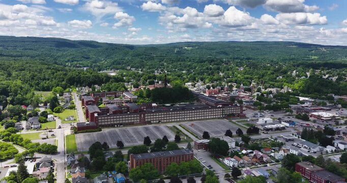 LLION, NY, USA - June 24, 2026: Afternoon summer aerial video of downtown, business district, LLION, NY.  Former Remington Arms factory brick building.