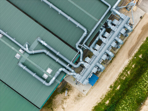 Aerial view of industrial facility roof with complex ventilation pipe system and green metal roofing in Upmalas, Sigulda Municipality, Latvia.