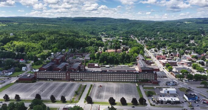 LLION, NY, USA - June 24, 2026: Afternoon summer aerial video of downtown, business district, LLION, NY.  Former Remington Arms factory brick building.