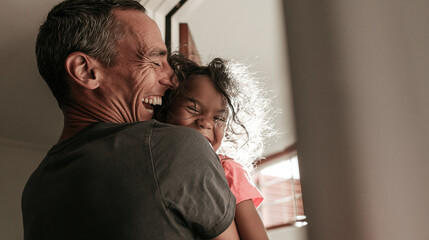 Fototapeta premium Joyful Embrace: A father shares a heartwarming moment with his daughter, their faces alight with laughter and affection.