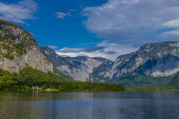 Fototapeta premium Hallstatt, Austria - 05.05.2025: Scenic view of Hallstatt, a historic lakeside village in Austria, nestled between the shores of Hallstatter See and the dramatic peaks of the Dachstein Alps