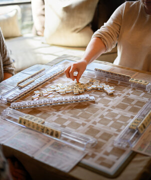 Mahjong game in play on the table with players choosing tiles and keeping score.