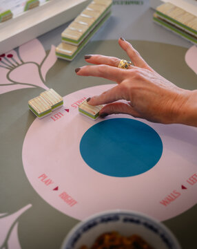 Mahjong game in play on the table with players choosing tiles and keeping score.