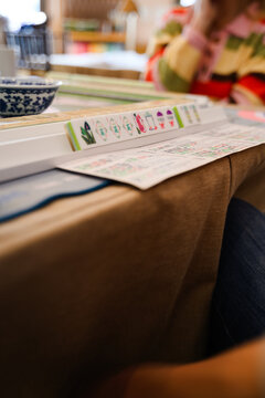 Mahjong game in play on the table with players choosing tiles and keeping score.