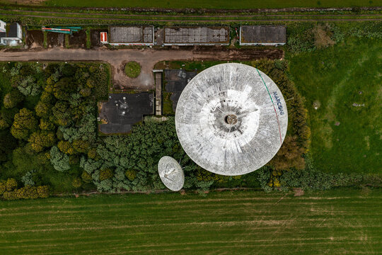 Aerial view of the Marconi satellite dish on Sao Miguel Island, surrounded by lush green fields and dense vegetation in the Azores, Portugal.