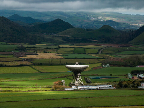 Aerial view of the radio telescope on Sao Miguel Island surrounded by green pastures and rolling hills in Azores, Portugal.
