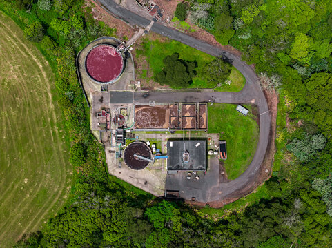Aerial view of the Tecnovia Acores industrial facility, featuring circular treatment tanks, rectangular basins, and surrounding green landscape in Rabo de Peixe, Acores, Portugal.
