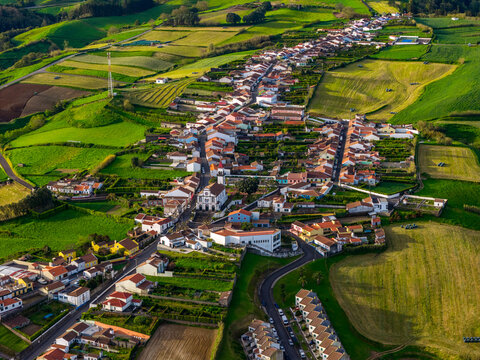 Aerial view of the village of Salga surrounded by vibrant green pastures and rolling hills in Salga, Azores, Portugal.