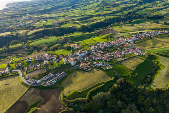 Aerial view of the village of Salga nestled among lush green agricultural fields and rolling hills on the island of Sao Miguel in Salga, Azores, Portugal.