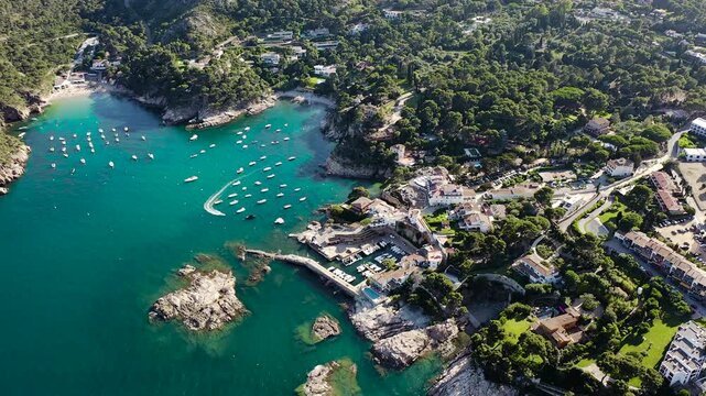 Aerial view of Aiguablava Beach, one of the most beautiful coves on the Costa Brava, featuring crystal-clear turquoise waters, rocky islets and lush Mediterranean pine forests. 