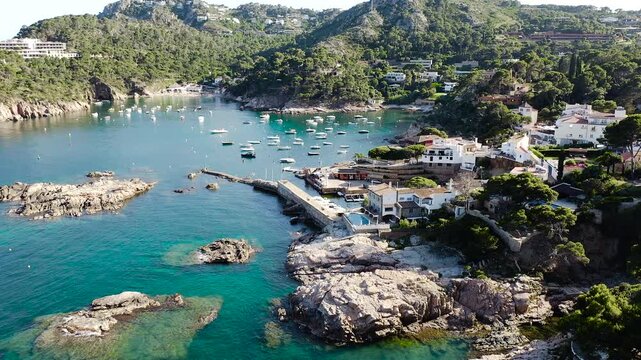 Aerial view of Aiguablava Beach, one of the most beautiful coves on the Costa Brava, featuring crystal-clear turquoise waters, rocky islets and lush Mediterranean pine forests. 