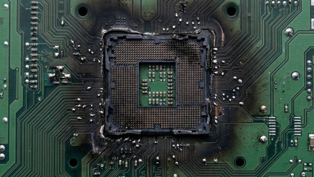 Technology - Burned and Melted CPU Socket on Damaged Green Motherboard After Electrical Overload Failure