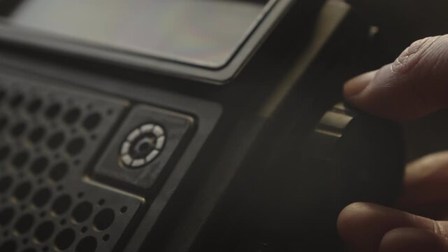 Close-up of a hand adjusting controls on a classic audio system in a dimly lit environment. Conveys nostalgia, analog media appreciation, and vintage listening rituals.
