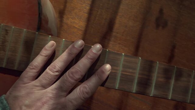 A slow-motion hand movement across a weathered stringless guitar evokes nostalgia, lost melodies, and a deep connection to musical memories and creative legacy.