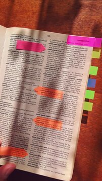 A language learner marks important sections in a dictionary using colorful tabs. Represents literacy, self-improvement, education, and effective study techniques.