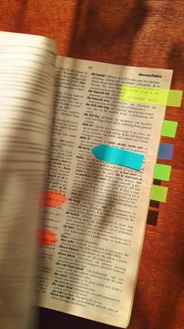 A learner organizes a dictionary with sticky tabs to improve vocabulary lookup and study efficiency. Perfect for education, literacy, and academic achievement themes.