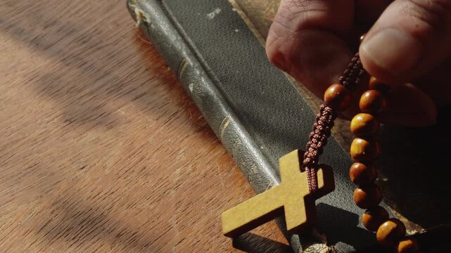 Close-up of a worshipper using rosary beads in silent prayer. Ideal for themes of faith, devotion, meditation, spirituality, and personal religious practice.