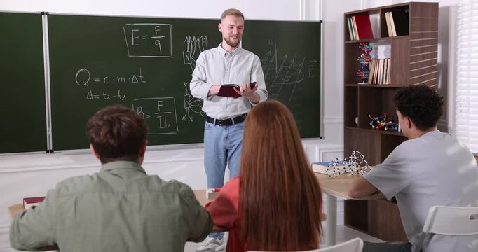 Teacher explaining information to students during physics lesson in classroom
