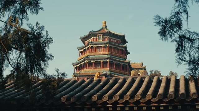 Beijing Close-up of the ornate, multi-tiered Buddhist Incense Tower at the Summer Palace framed by silhouettes of pine branches